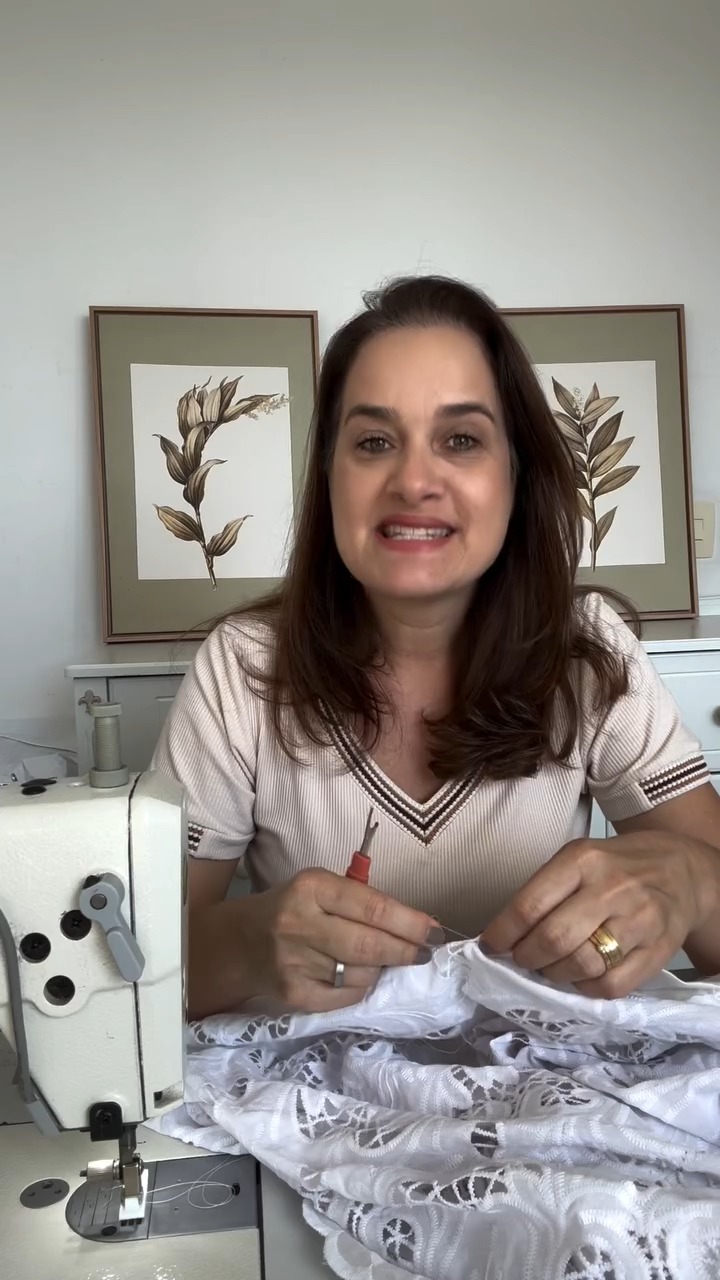 Jesiane sorrindo no seu ateliê, costurando
